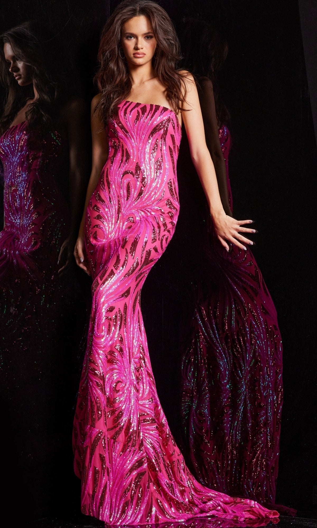 A woman in the Jovani One-Shoulder Sequin Long Prom Dress 23876 stands against a black background, showing off the gown’s floor-length silhouette and dazzling sequin details, with her reflection visible.